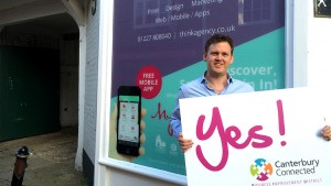 A man outside Think Agency holding a sign that says Yes! Canterbury Connected BID