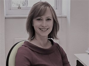 A photo of a woman named Lisa sitting at a desk and smiling