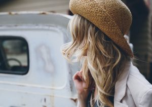 A young blonde woman wearing a straw hat and looking away from the camera