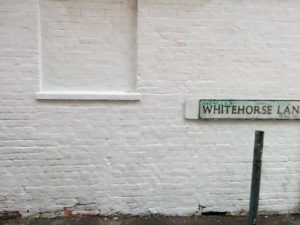 A white brick wall that has been cleaned of graffiti Whitehorse Lane