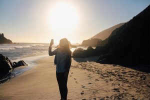 A girl on a beach taking a picture with her phone