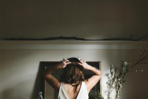 A bride looking in the mirror and putting a flower crown on her head