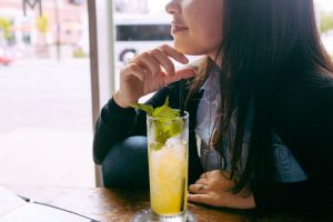 A girl sitting at a table with a long island iced tea