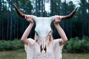 A bride holding a buffalo skull in front of her face