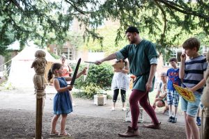 A Medieval Pageant actor pretending to sword fight with a small girl