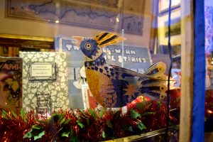 A blue and yellow paper bird in a shop window