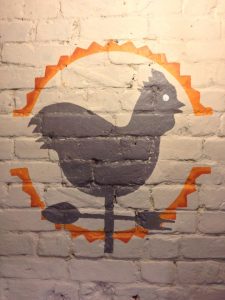The logo of Refectory Kitchen on a white brick wall
