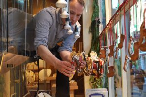 A man arranging hanging gingerbread decorations in a Ortwin Thyssen window