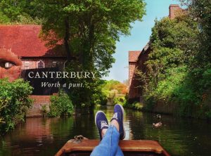 A photo of a persons legs cruising in a river boat with text over it that reads Canterbury - Worth a punt