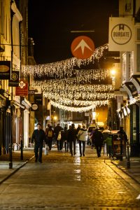 A busy Canterbury high street at night, lit by hanging christmas lights
