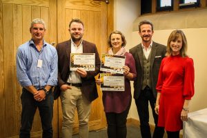 Some people smiling for a photo and holding School Competition award certificates