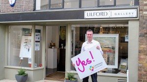 A man outside Lilford Gallery holding a sign that says Yes! Canterbury Connected BID