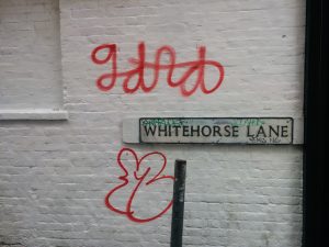 Graffiti on a white brick wall on Whitehorse Lane