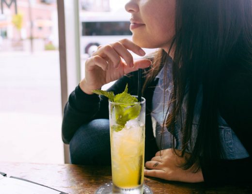 A girl sitting at a table with a long island iced tea