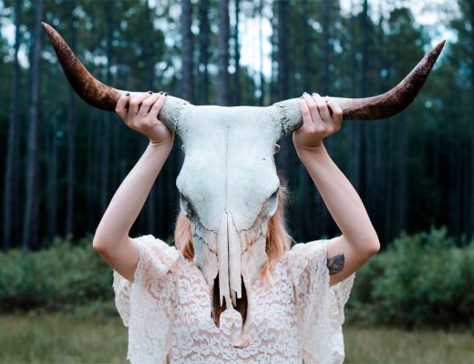 A bride holding a buffalo skull in front of her face