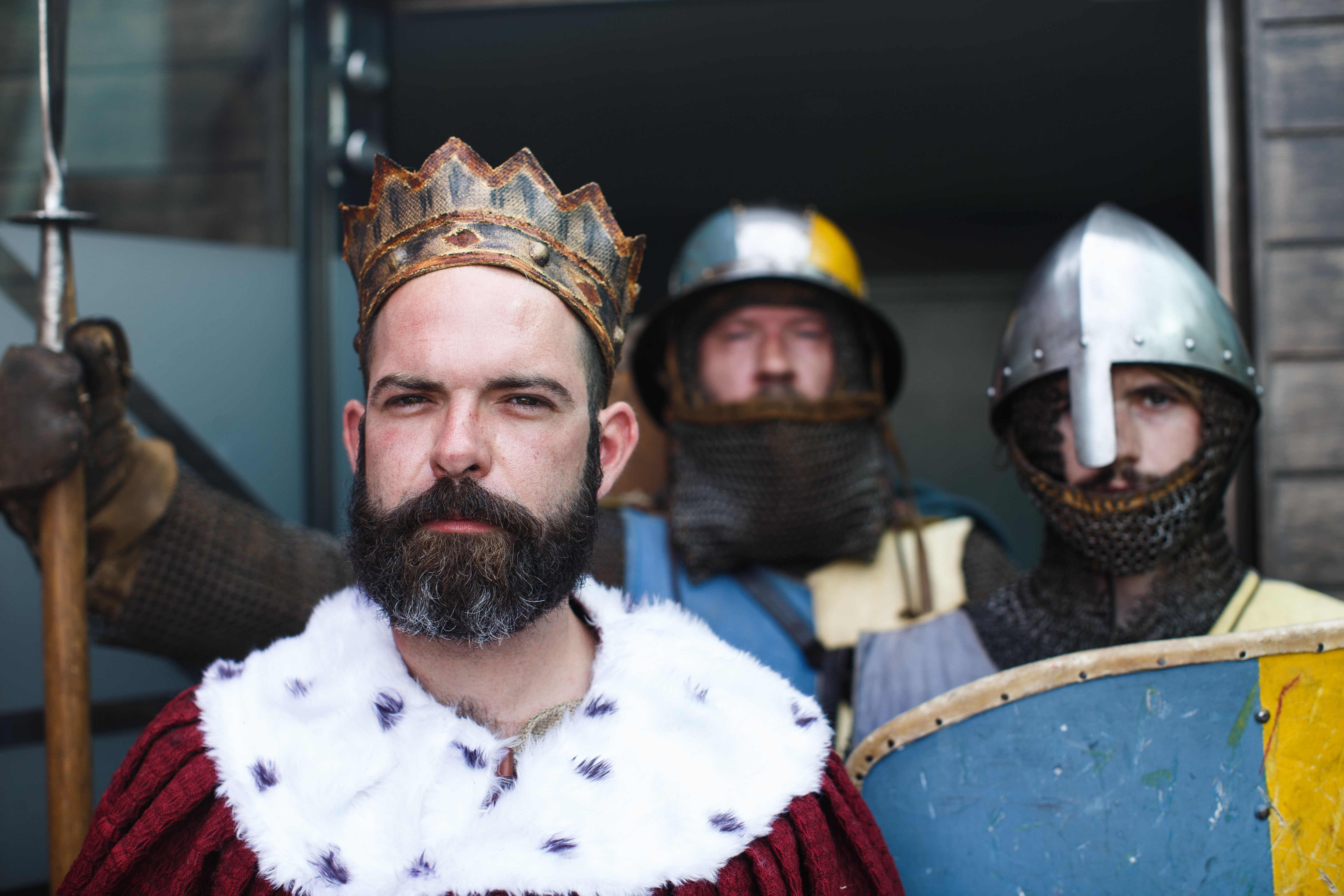 Three men, one dressed as a medieval king and two as knights