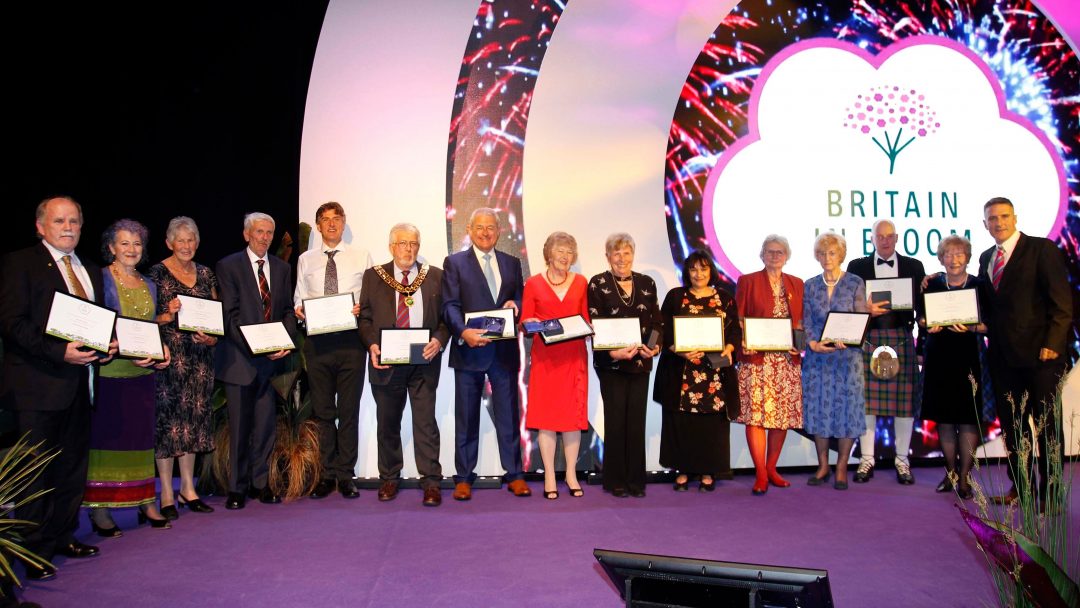 Britain in Bloom award winners taking a celebratory photo together, all holding their award certificates