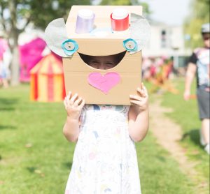 A child with a box helmet resembling a creature on her head