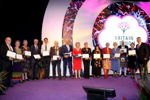 Britain in Bloom award winners taking a celebratory photo together, all holding their award certificates