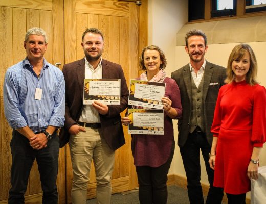 Some people smiling for a photo and holding School Competition award certificates