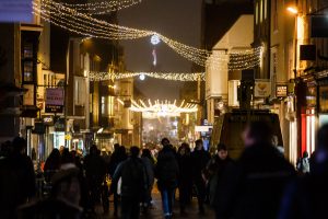 A busy Canterbury high street at night, lit by hanging christmas lights