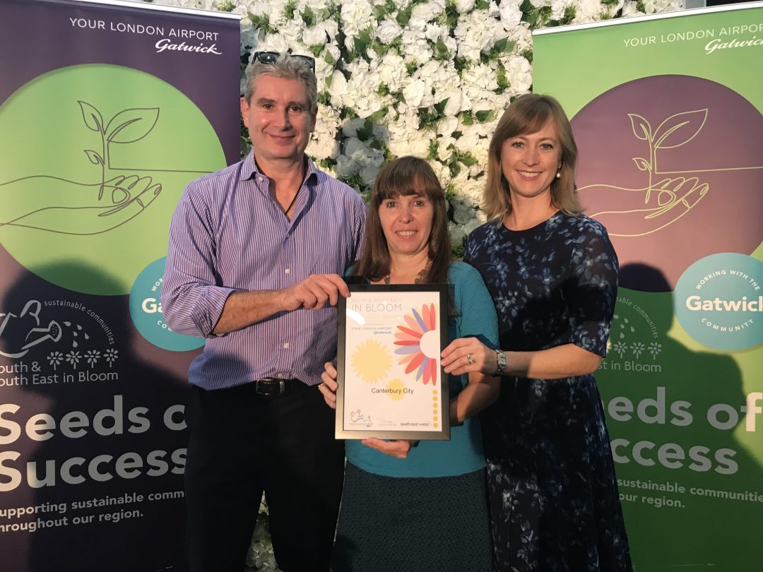 Two women and a man posing for a photo together holding a Canterbury in Bloom award certificate