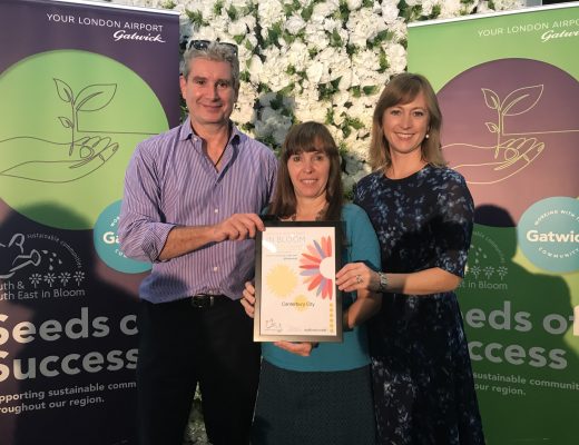 Two women and a man posing for a photo together holding a Canterbury in Bloom award certificate