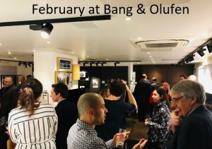 A photo of a room of people socialising, with text above it that reads February at Bang & Olufen