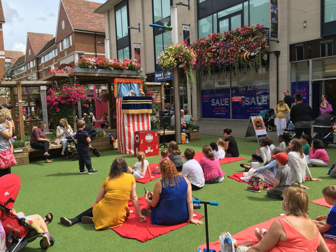 Some people sitting on the floor and watching a Punch and Judy show