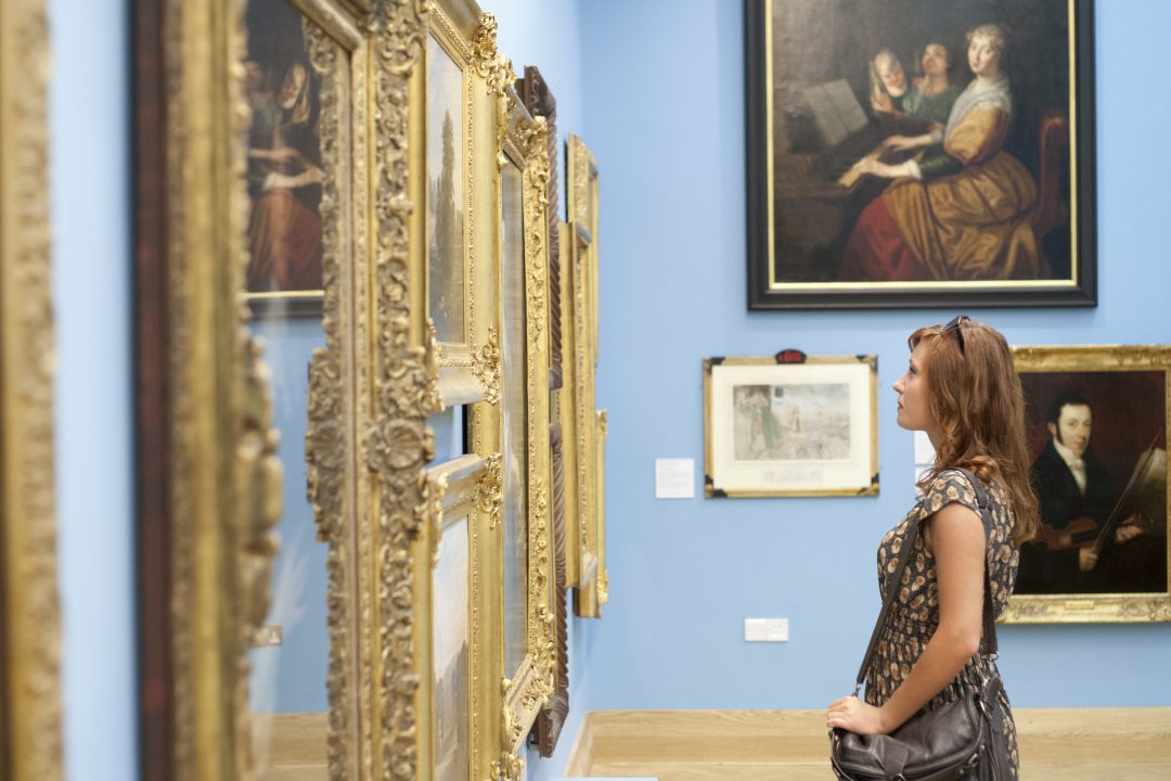 A photo of a woman in The Beaney gallery, admiring a painting