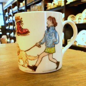 A mug with an illustration of a woman walking her dog on it
