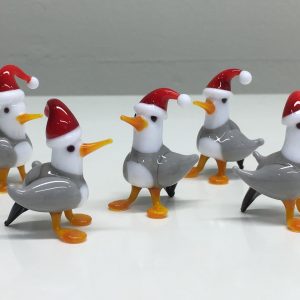 A photo of some glass seagulls wearing Santa hats