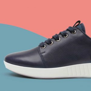 A photo of a black trainer shoe on a blue and coral background