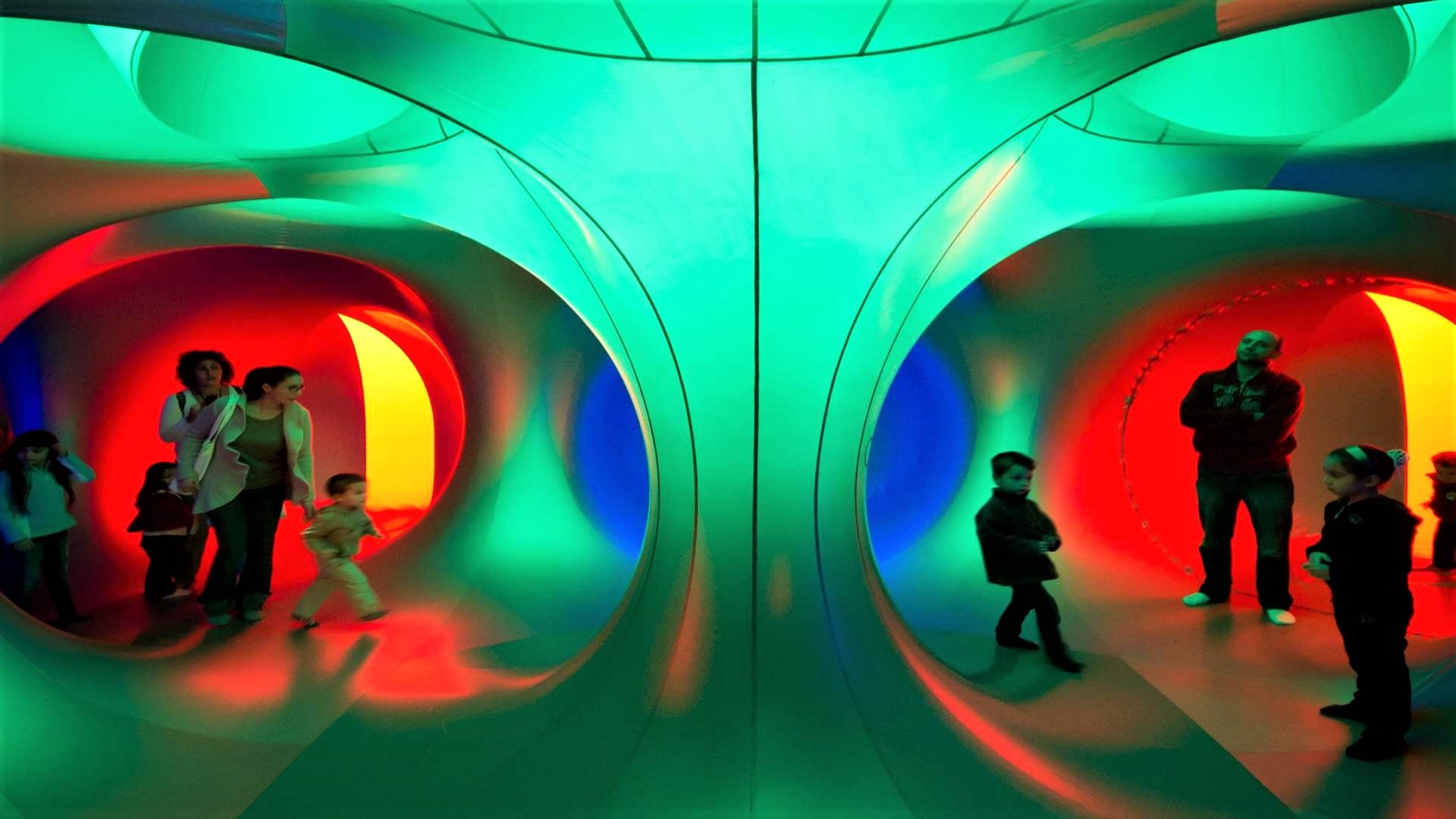 A photo of some family's experiencing a colourful indoor exhibit