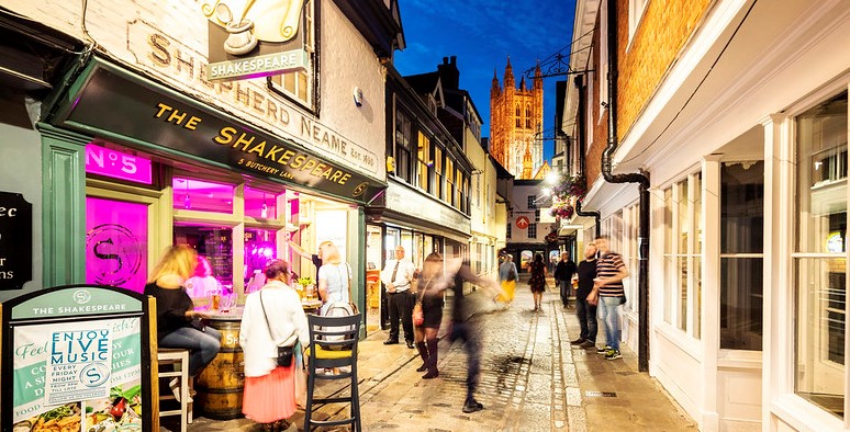 A photo of a Canterbury street at night, with The Shakespeare pub in the foreground and Canterbury Cathedral in the background