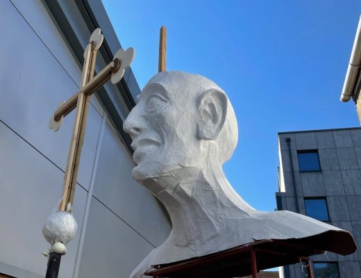 A photo of a model giant holding a crucifix being made