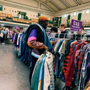A photo of a man, amongst others, shopping for clothes at a Worth the Weight vintage kilo sale
