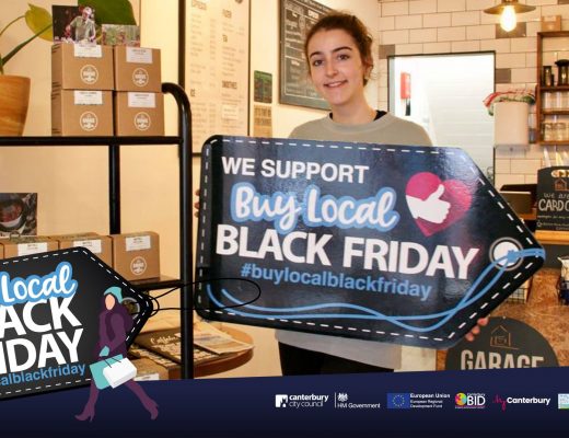 A photo of a woman holding a sign that says we support buy local black friday #buylocalblackfriday