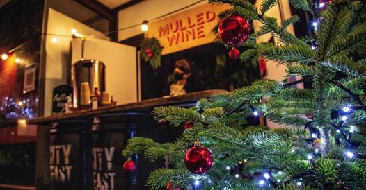 A photo of a bar selling mulled wine, with a christmas tree in the foreground