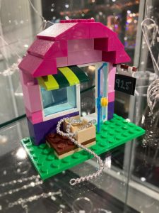 A photo of a small shop made of Lego in a glass case