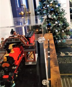 A photo of a steam train and train station made of Lego, with a Christmas tree in the background