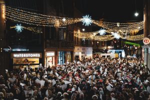 A photo of a large crowd in the streets of Canterbury taking part in a carol service