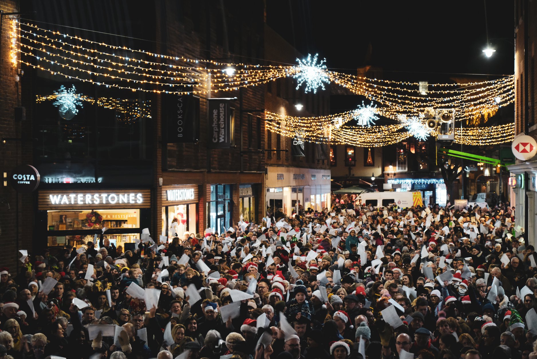 A photo of a large crowd in the streets of Canterbury taking part in a carol service