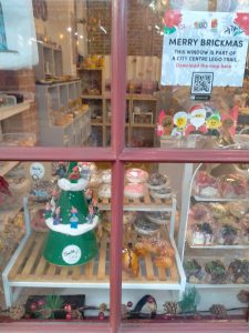 A photo of a small christmas tree with Lego figures on it in a shop window