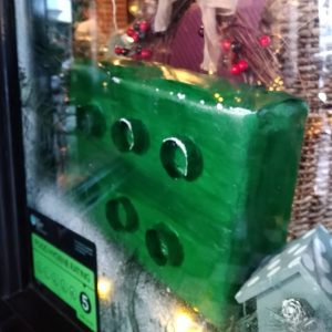 A photo of a large decorative green Lego brick in a shop window