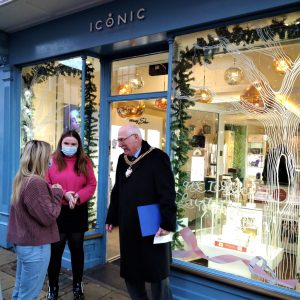 A photo of two women talking to a mayor outside of a shop named iconic