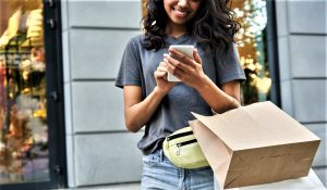 A photo of a woman on her phone with shopping bags on her arm