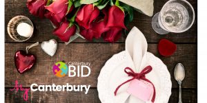 A photo of some roses and valentines table decor with a Canterbury BID MyCanterbury logo over it