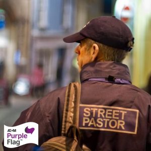 A photo of a man wearing a street pastor jacket from behind