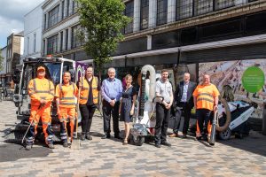 A group photo of some people in a high street with public cleaning equipment